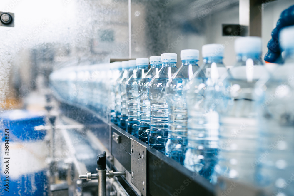 Bottling plant - Water bottling line for processing and bottling pure spring water into blue bottles. Selective focus. 