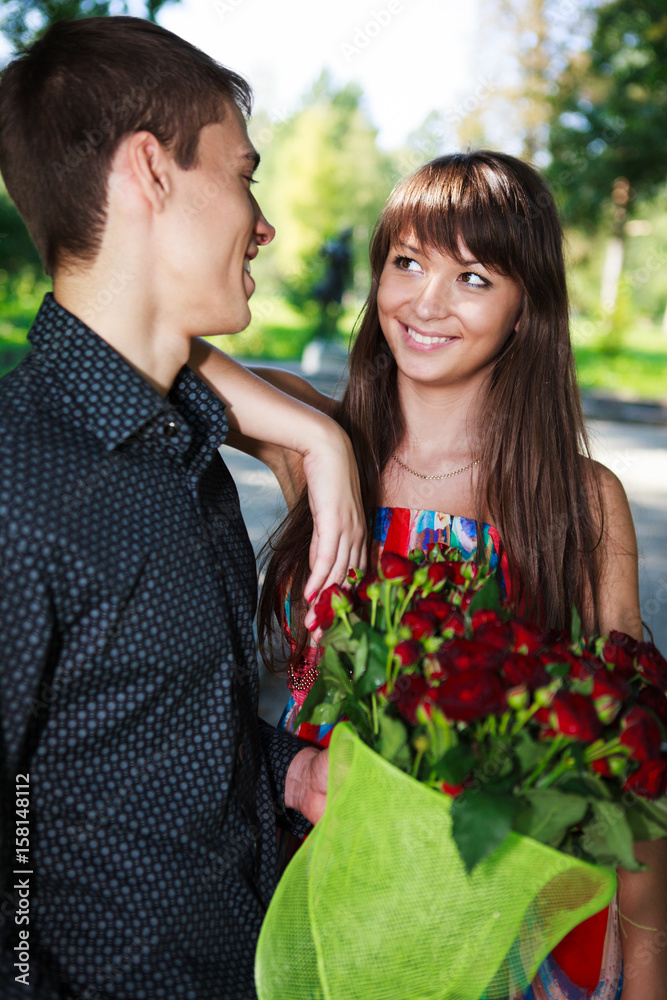 Portrait cheerful young couple with a bouquet of red roses Portrait cheerful young couple with a bouquet of red roses