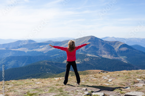 Hiker standing on a peak over the mountain with raised hands
