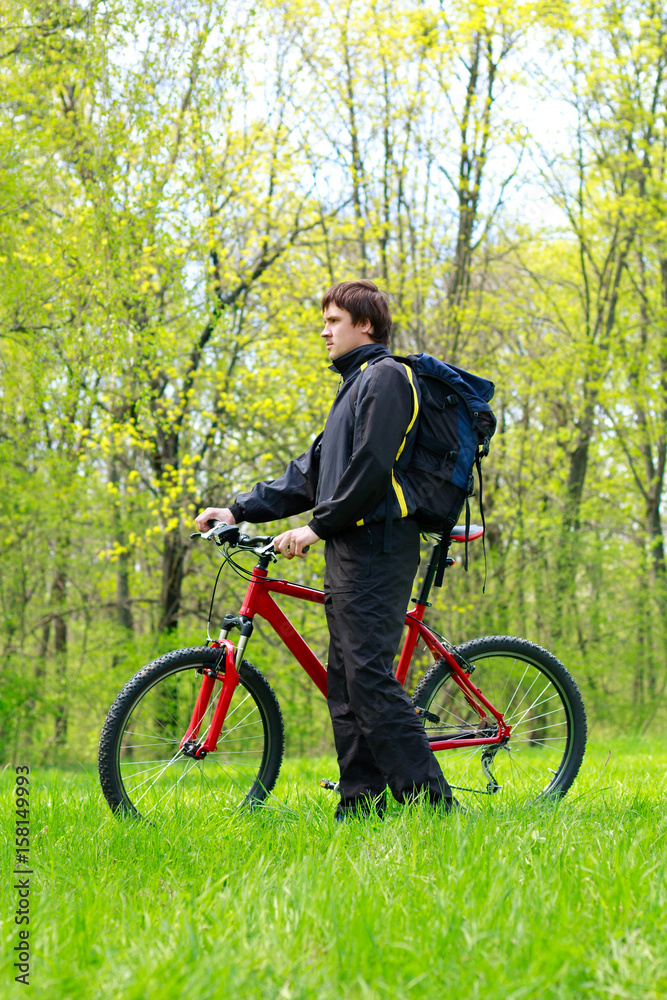 Fototapeta premium Man Cyclist with Bike and Backpack among the green nature