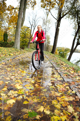 Cyclist ride through a puddle in the autumn park