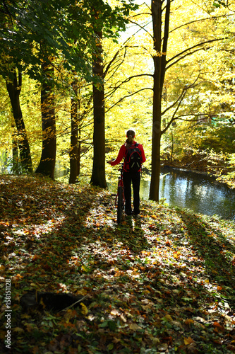 Young woman cyclist in the autumn sunny park