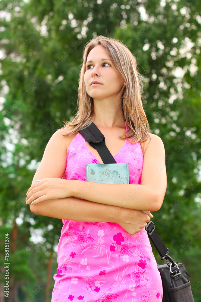 Young woman with book in hand and a bag over his shoulder