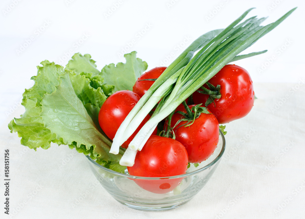 Branch of tomatoes, green onions, herbs lettuce in a salad-bowl