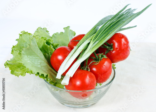 Branch of tomatoes, green onions, herbs lettuce in a salad-bowl