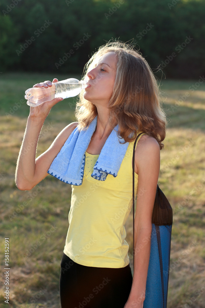 Young woman drinking water after outdoors workout on a park Young woman drinking water after outdoors workout on a park