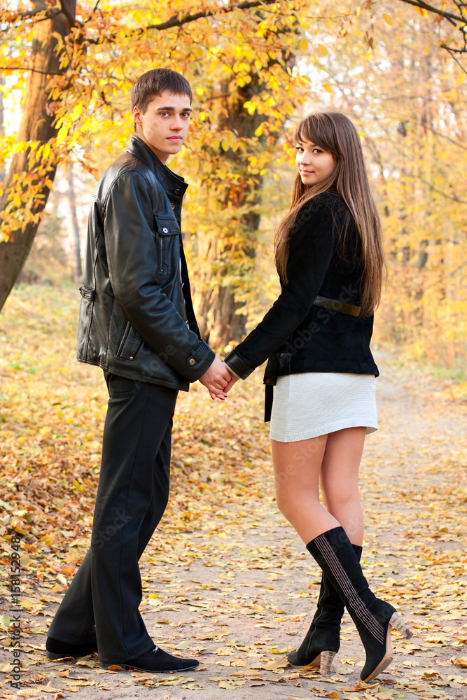 Young beautiful couple in love holding hands of autumn park Young beautiful couple in love holding hands of autumn park