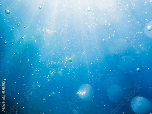 Bubbles underwater in sea and sun rays. Water texture in ocean