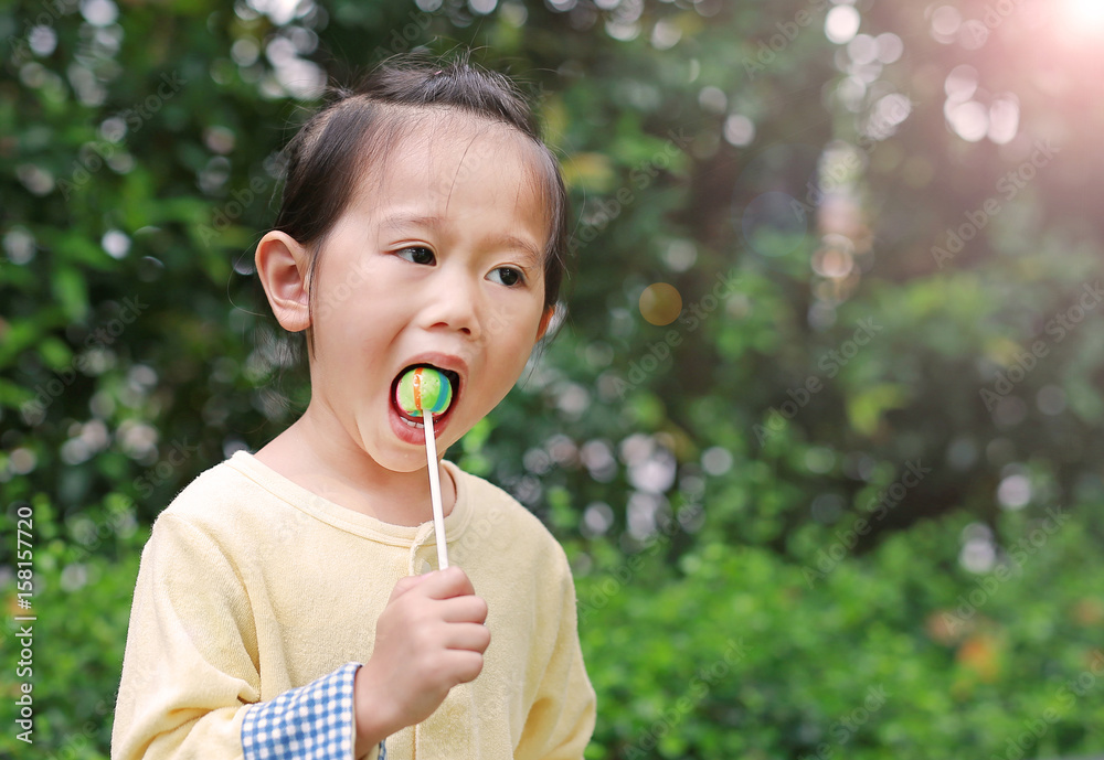 Little child girl enjoy eating lollipop candy in the park. Little child girl enjoy eating lollipop candy in the park.