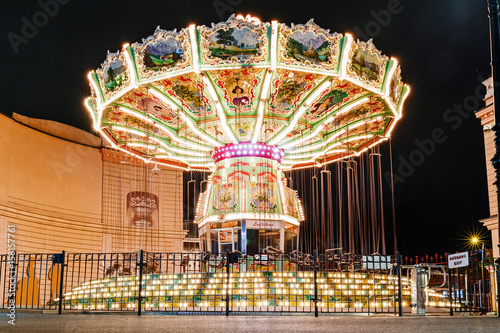 Children's Carousel at an amusement park in the evening with night lights illumination photo