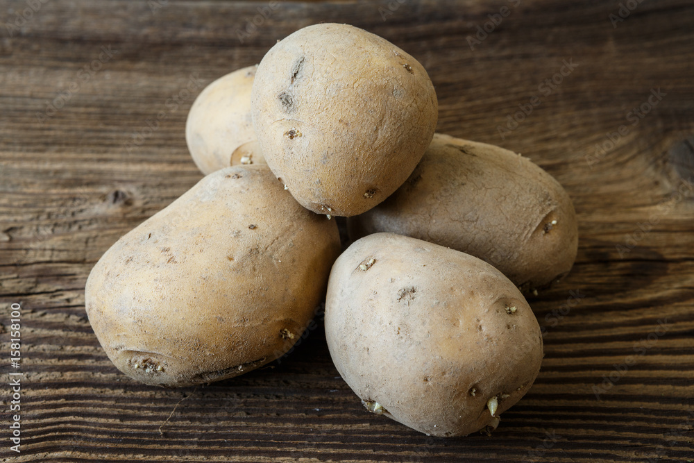 Pile of old potatoes with sprouts on rustic wooden table Pile of old potatoes with sprouts on rustic wooden table