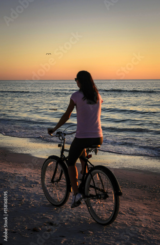 Young woman rides her bicycle along the Siesta Key beach in Florida at sunset © csfotoimages