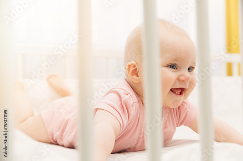 cute happy baby girl playing in crib