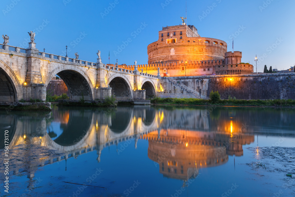 Saint Angel castle and bridge and Saint Peter Cathedral with mirror reflection in Tiber River during morning blue hour in Rome, Italy.