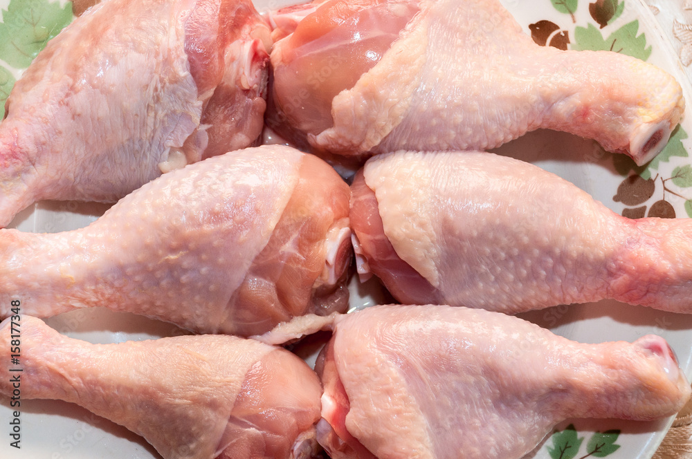 Not cooked chicken thighs lie on a plate Not cooked chicken thighs lie on a plate
