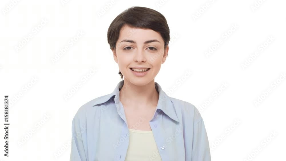 Young brunette Caucasian girl with short hairstyle looking calmly at camera and smiling. Footage on white background