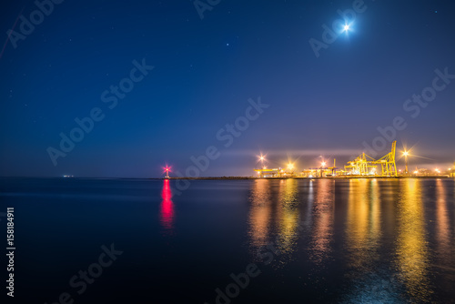 A view of the port facilities, a small lighthouse at the entrance to the port. Night photo.