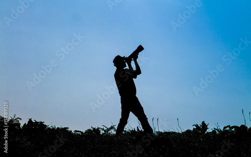 Silhouette of photographer on sky background