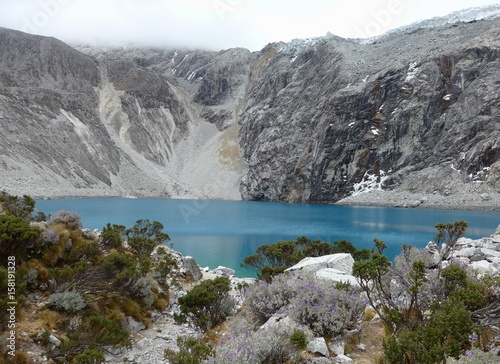 Vibrant blue waters of Laguna 69 beautifully contrasted against a dark grey rock backdrop. 