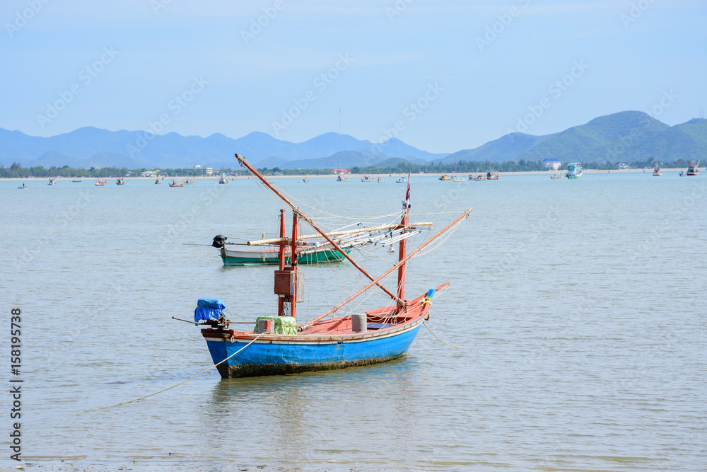 Beachfront scenery with fishing boats landing at Prachuap Khiri Khan, Thailand.
