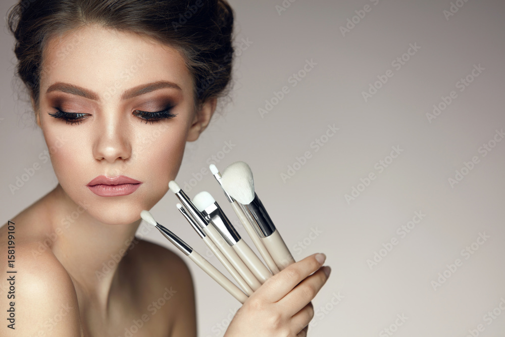 Makeup Cosmetics. Glamorous Beautiful Woman Holding Brushes - obrazy, fototapety, plakaty 