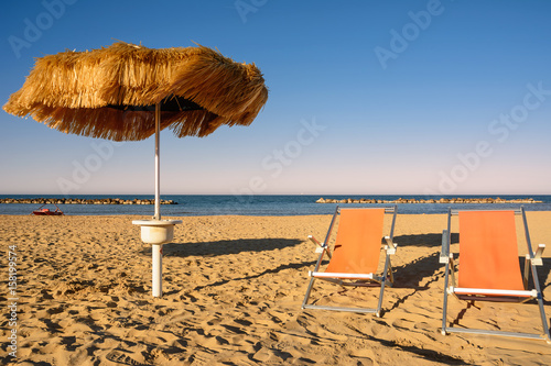 Palm umbrellas on the beach and pier in background in Francavilla al Mare (Italy)