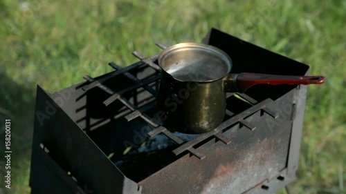 Mug with boiling water on a brazier photo