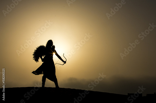 young woman with a bow and an arrow in a desert photo