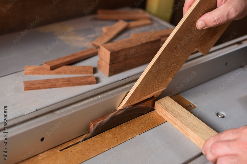 Carpenter sawing wood detail on circular saw hepling with stick for safety Carpenter sawing wood detail on circular saw hepling with stick for safety