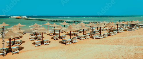 Chaise lounge and parasols on the beach against the blue sky and sea. Egypt, Hurghada