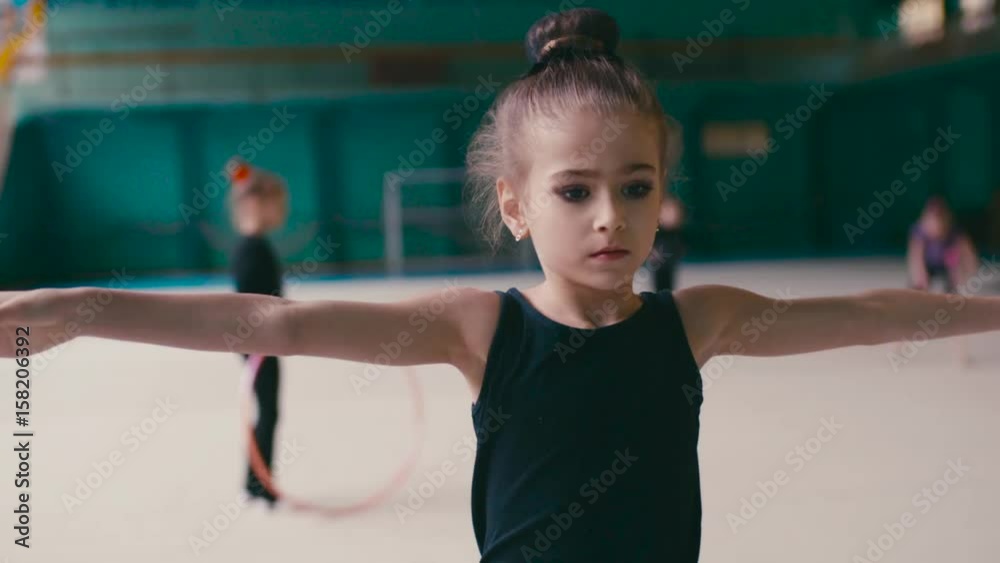 Adorable little gymnast performs the gymnastic training, does the vertical split several times. Being healthy and fit, go into sport. Active lifestyle, sportive kids. Happy childhood. Adorable little gymnast performs the gymnastic training, does the vertical split several times. Being healthy and fit, go into sport. Active lifestyle, sportive kids. Happy childhood.