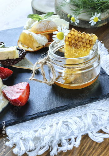 Sweet honeycombs and bank with honey on wooden table on natural background