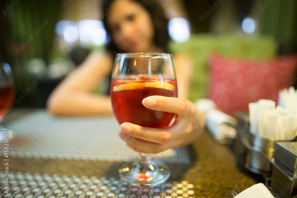 A girl drinks a red strawberry drink in a restaurant