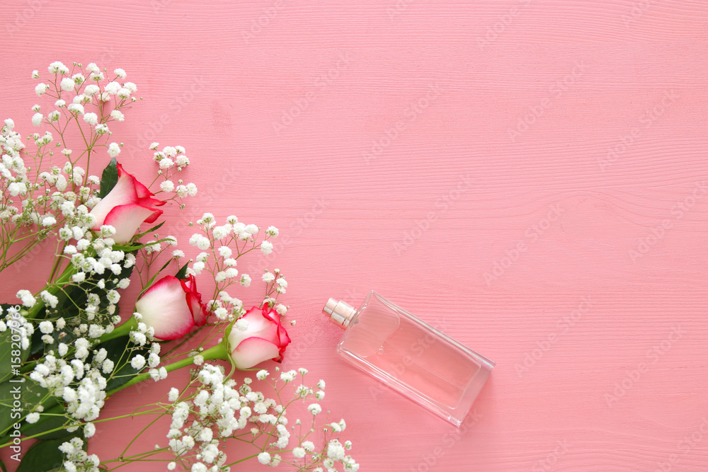 beautiful roses next to perfume on wooden background. beautiful roses next to perfume on wooden background.