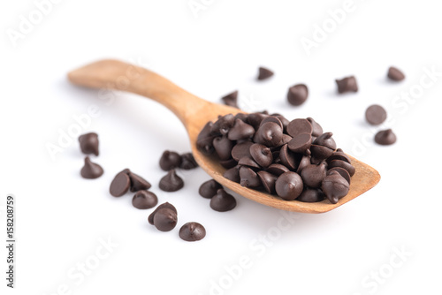 Dark chocolate chips in spoon isolated on white background.