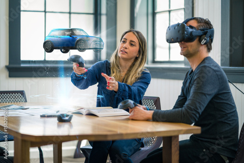 Business colleagues review automotive design concepts wearing a virtual reality headset. © db