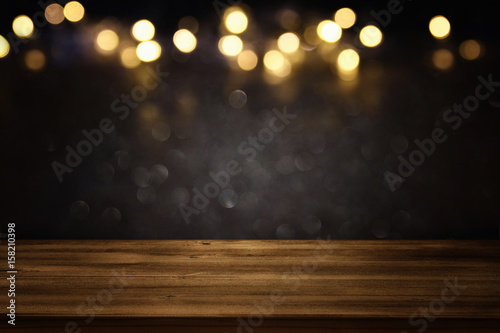 Photography Empty table in front of black and gold glitter lights background