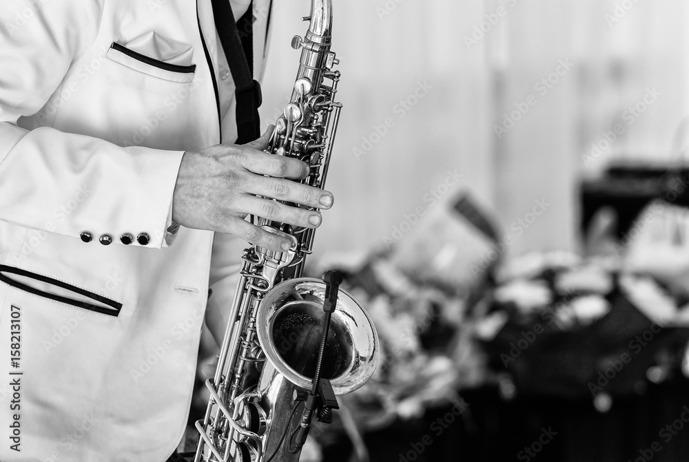 Fototapeta premium Saxophonist in white jacket plays the saxophone. Saxophonist jazz man with saxophone on wedding party
