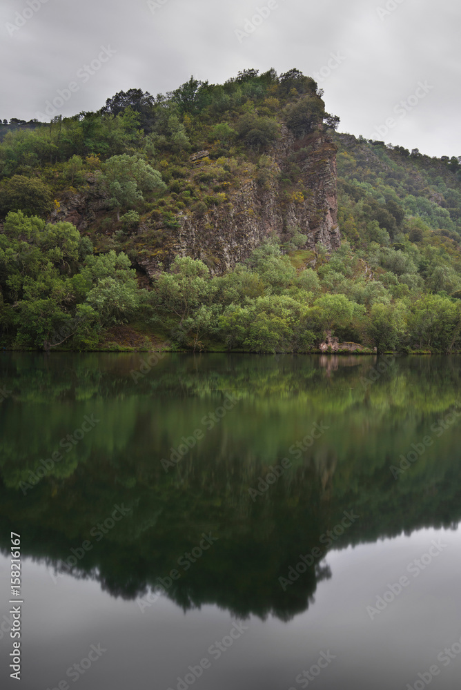 Scenic landscape of reflections and ruins in a tranquil lake on a cloudy day, La Rioja, Spain.