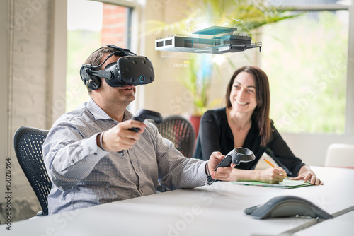 Business colleague wears a virtual reality headset and interacts with 3D model. © db