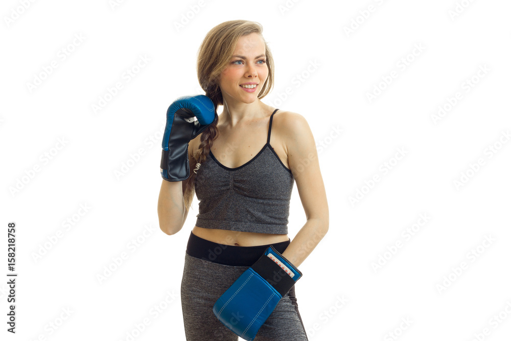 a cheerful athletic girl with a pigtail and boxing gloves looks toward a cheerful athletic girl with a pigtail and boxing gloves looks toward