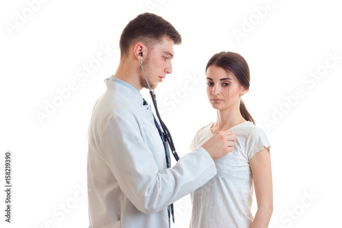 doctor with stethoscope in your ears listening to the heart and lungs of a young woman