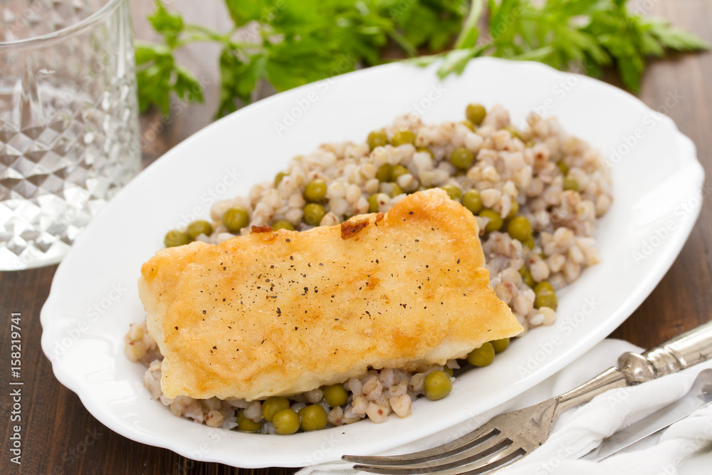 fried fish with boiled buckwheat and peas in white dish