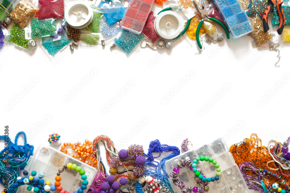 Colorful beads, pliers and bijouterie lie on a white background.
