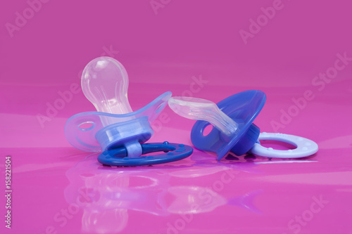 two pacifiers on pink background