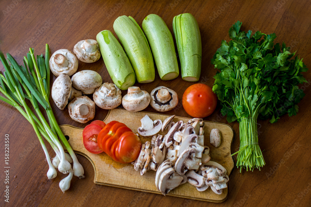 Raw vegetables and mushrooms on a wooden board cut for cooking. Raw vegetables and mushrooms on a wooden board cut for cooking.