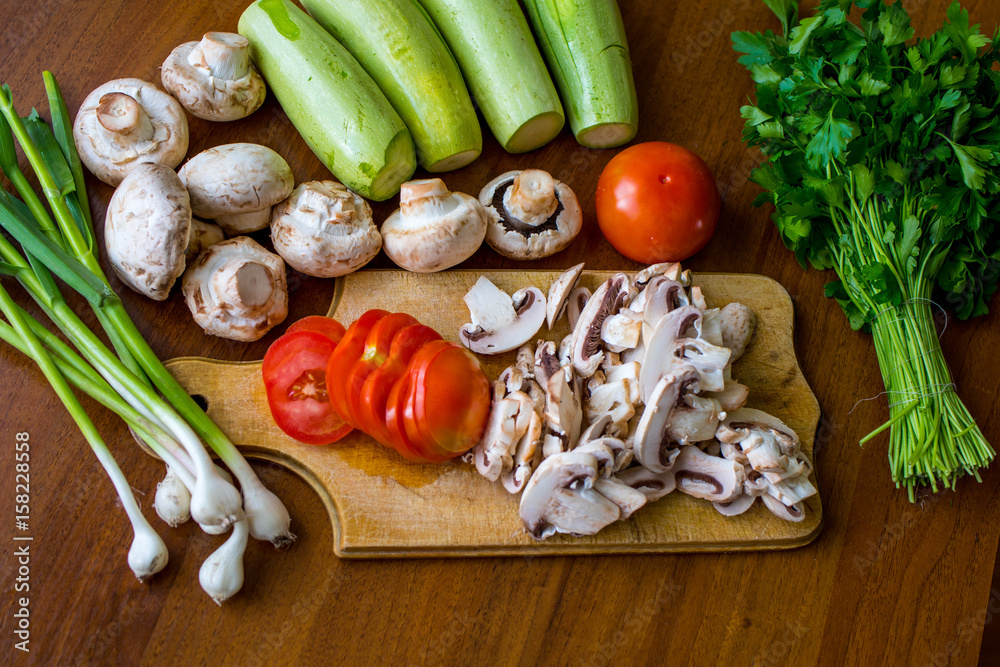 Raw vegetables and mushrooms on a wooden board cut for cooking. Raw vegetables and mushrooms on a wooden board cut for cooking.