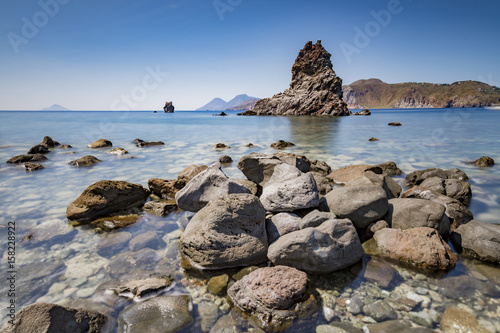 Baia rocciosa con vista sul faraglione e le isole di Lipari e Salina dietro, isola di Vulcano IT