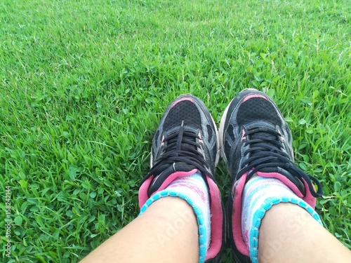 runner girl and running shoes selfie with green grass background.
