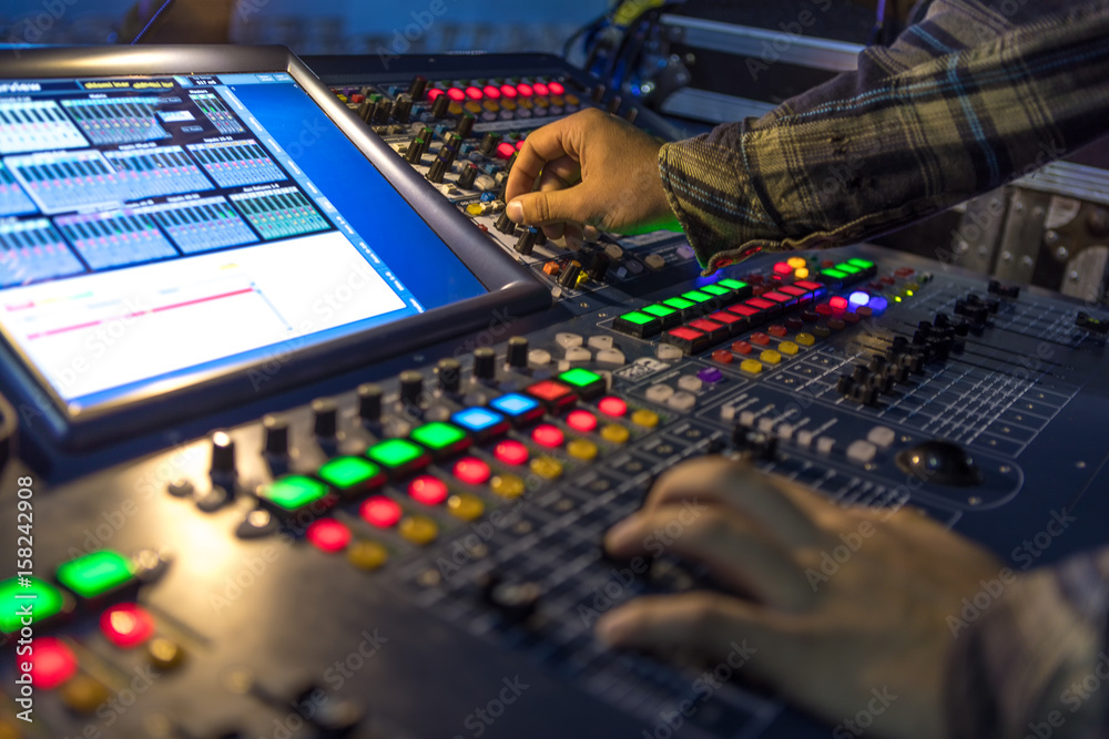 Two hands on a audio mix control board console